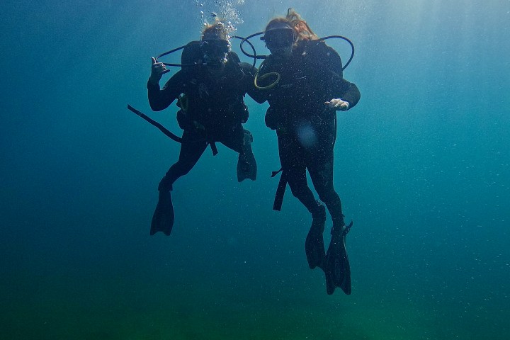 Two scuba divers underwater with rays of light shining through.