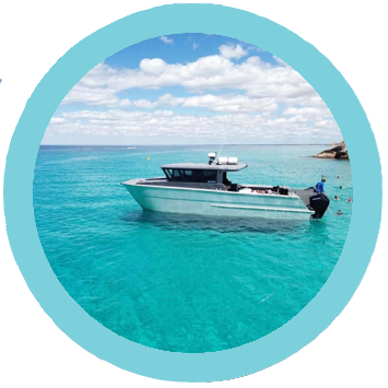 Small boat floating on clear turquoise water under a blue sky with clouds.