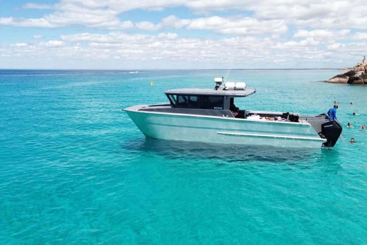 Boat floating on clear turquoise water under a partly cloudy sky.